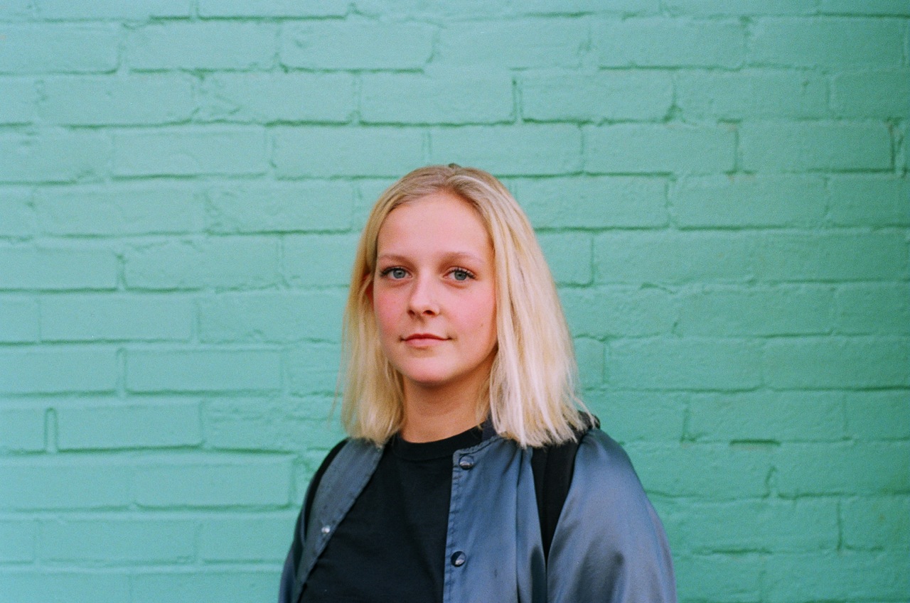 Young woman in front of aqua green wall